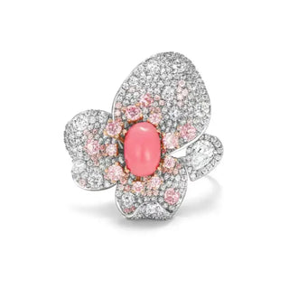 Floral cocktail ring in sterling silver featuring a central coral stone and pink lab sapphires arranged in a petal-inspired design.
