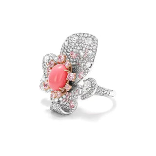 Floral cocktail ring in sterling silver featuring a central coral stone and pink lab sapphires arranged in a petal-inspired design.