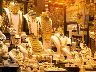 Gold bangles displayed in a Dubai souk shop window with price tags attracting tourists