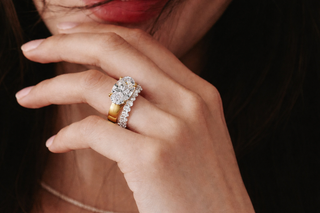 East west oval diamond engagement ring in yellow gold with a pavé diamond band on a woman's hand