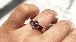 A person crafting an engagement ring at a jewelry workbench, surrounded by tools, gemstones, and a wax mold—highlighting the creative appeal and challenges of making a DIY engagement ring.