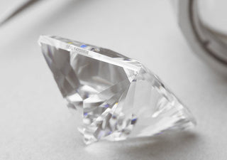 Close-up of a loose diamond showing a microscopic laser inscription etched on the girdle for identification.