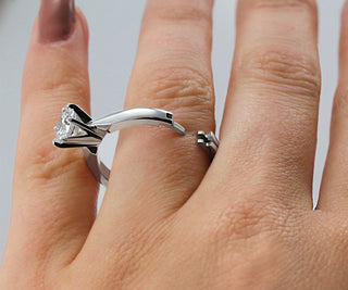 Hinged platinum solitaire ring opened on finger, showing how it bypasses the knuckle easily