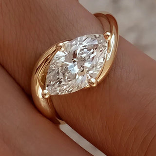 Marquise diamond set horizontally on a curved yellow gold band, designed with a sleek modern style.