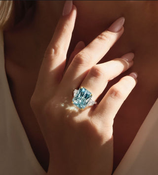 A jeweler in Dubai presenting a custom engagement ring design to a couple, with sketches, gemstones, and sample settings on display.