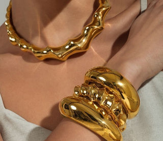 A curated display of essential jewelry pieces including gold hoops, a tennis bracelet, layered necklaces, and classic studs on a neutral background. 