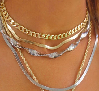 A close-up of layered gold, silver, and rose gold necklaces and rings styled together for a trendy, mixed-metal look.