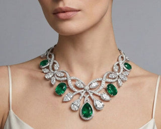 Emerald and diamond necklace with flowing vintage inspired design worn on a model’s neckline