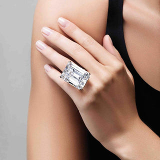Woman wearing an oversized emerald cut diamond ring on her hand, showcasing a bold, high-carat statement piece.