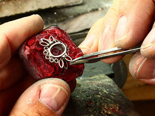 Side-by-side view of a craftsman handcrafting jewelry and a machine assembling pieces, highlighting the contrast between handmade and machine-made methods.