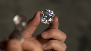 Close-up of polished diamond between index finger and thumb