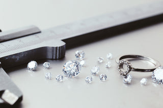 A hand holding a magnifying glass over a pre-owned diamond ring, highlighting its quality and value.