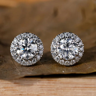 A hand holding multiple pairs of diamond stud earrings in varying sizes to help choose the right carat weight.
