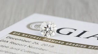 Round brilliant cut diamond placed on top of a GIA natural diamond grading report showing certification details and quality documentation