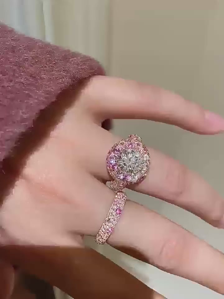 Video of Close-up of a luxurious engagement ring featuring a large round brilliant-cut white gemstone at the center, surrounded by multiple pink and white sapphires set in a rose gold band.