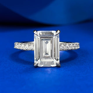 Sterling silver ring with an emerald-cut moissanite centerpiece in a classic prong setting, showcasing minimalist elegance.